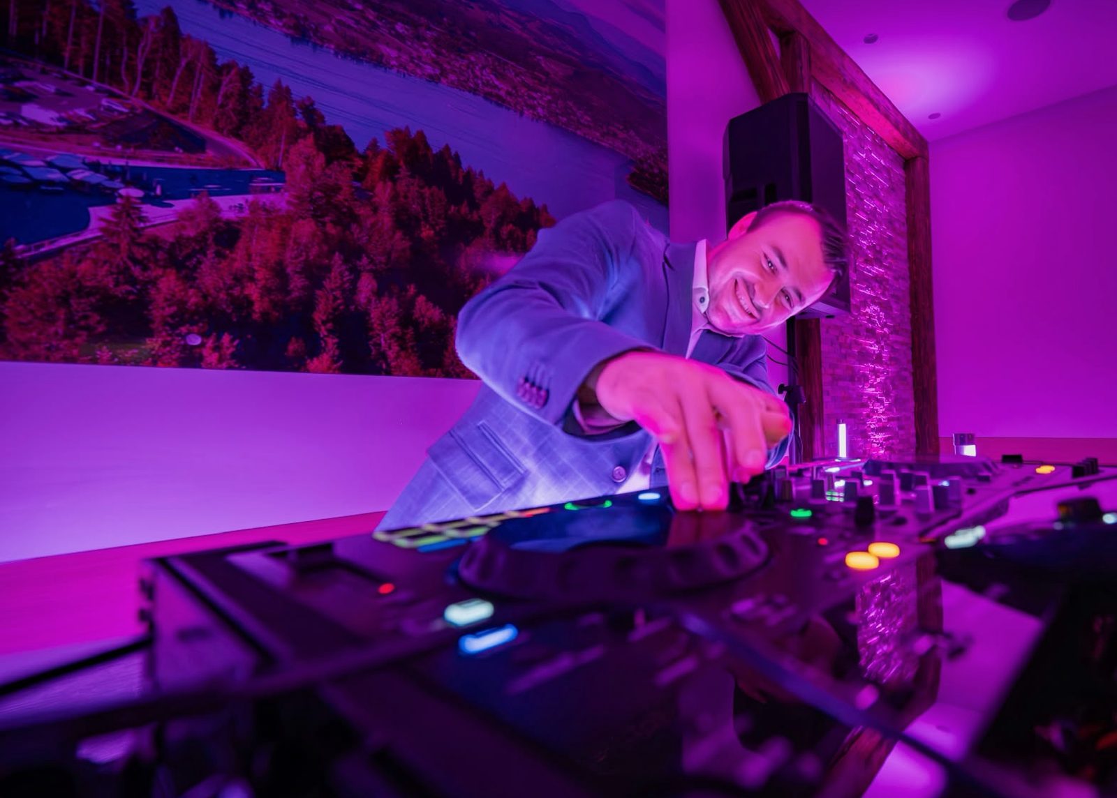 DJ Daniel Wulz im Sakko am DJ-Pult, der Raum in violettem Licht