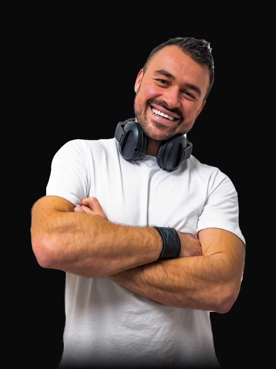 DJ Daniel Wulz lacht mit verschränkten Armen und Kopfhörern um den Hals, weißes T-Shirt vor weißem Hintergrund