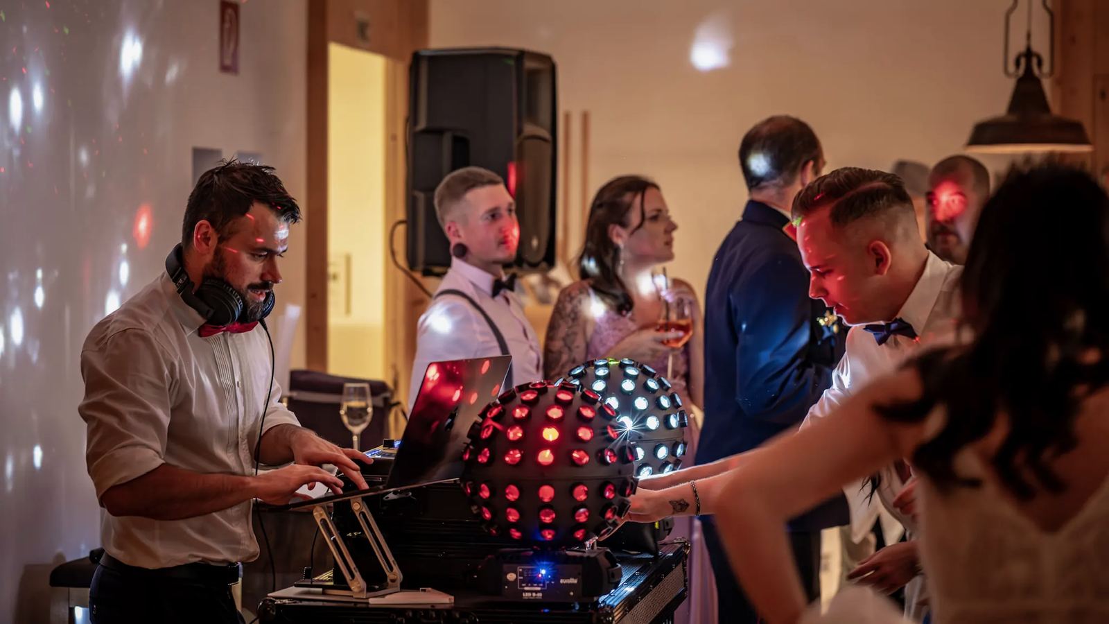 Hochzeitsgäste feiern direkt vor dem DJ-Pult, Daniel Wulz mit erhobenen Armen dahinter